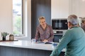 Couple chatting over coffee in a modern, light-filled kitchen in an independent living home.